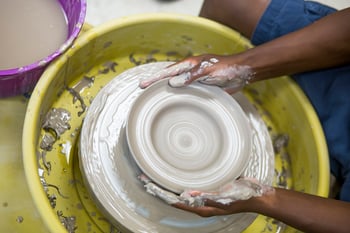 Student throwing clay on a potter's wheel