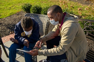 Middle School teacher shares an article on an iPad with a student outdoors