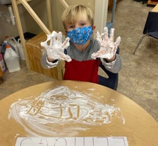 Student writes letters in shaving cream on table