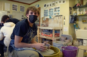 Upper school student throwing pottery on the wheel in ceramics class